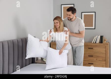 Couple putting pillows on bed at home. Domestic chores Stock Photo