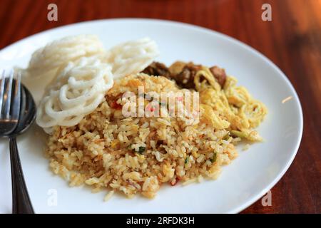 Nasi Goreng Spicy, Fried Rice with Kerupuk Shrimp Crackers. Served on White Plate Stock Photo