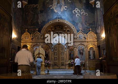 Worshipers pray in front of the altar of St Nicolas Church. Bucharest, Romania Stock Photo