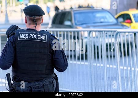 Russian police officer of National Guard in bulletproof vest patrol the city street. Translation of inscription on the male back: "Ministry of Interna Stock Photo
