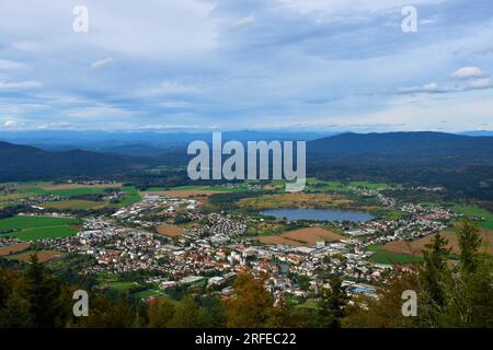 View of the town of Kocevje in summer surrounded by fields and forest covered hills behind Stock Photo