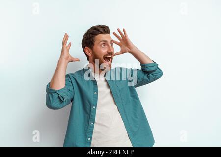 Surprised and shocked man standing on white background and screaming with rise arms Stock Photo