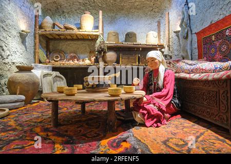 A diorama of a traditional Kazakh woman, sitting at home at a low table for a meal. At the old fortress, citadel museum in Shymkent, Kazakhstan. Stock Photo