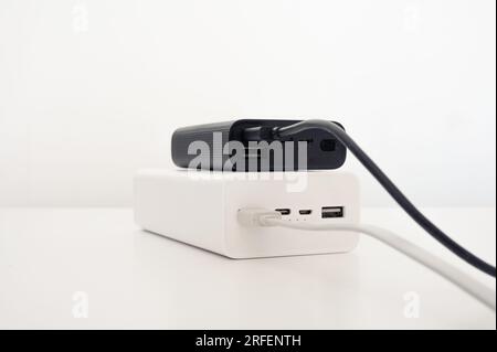 White power bank under black mobile charger with white and black cord cable connected. Stock Photo