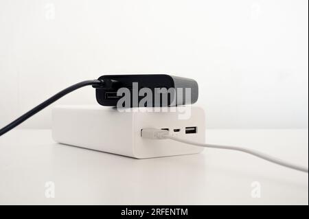 White power bank under black mobile charger with white and black cord cable connected. White background. Stock Photo
