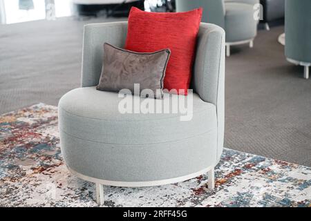 modern living room, single seater armchair grey sofa, with red and yellow cushion. Stock Photo