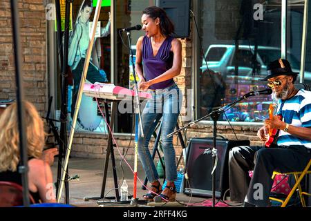 United States, Mississippi, Clarksdale, Caravan Music Fest, Shy Perry plays with her father Bill Howling Mad Perry in front of the Cat Head Delta Blues store Stock Photo