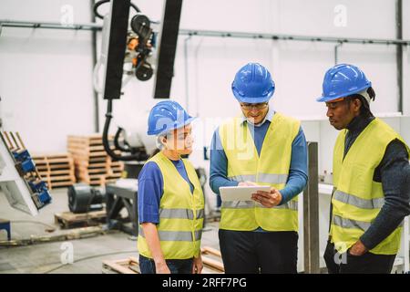 Engineers working at new AI prototype inside robotic factory - Future, job and technology concept - Mani focus on center man face Stock Photo
