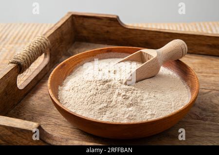 Psyllium husk flour powder on wood bowl and spoon indoors at home. Health benefits of Psyllium flour concept. Stock Photo