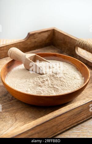 Psyllium husk flour powder on wood bowl and spoon indoors at home. Health benefits of Psyllium flour concept. Stock Photo