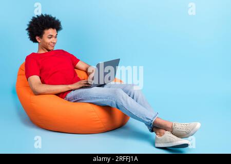 Full length body of young guy bean bag workplace young it specialist project manager using netbook isolated on blue color background Stock Photo
