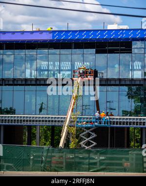 Construction workers installing glass panels on a new office building Stock Photo