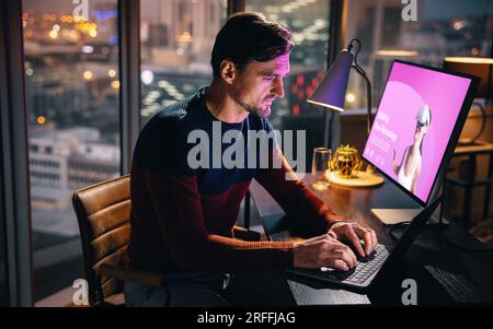 VR developer and designer working late in his office, using a laptop and a computer at his desk. He is dedicated, creative, and focused on completing Stock Photo