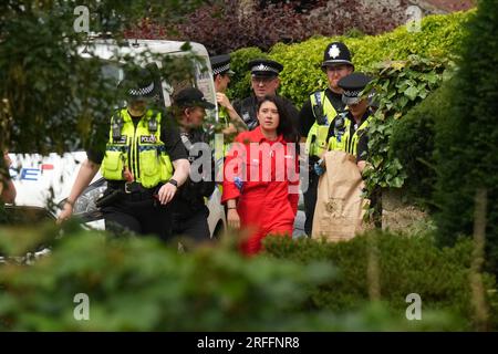 Greenpeace activists are led away by police after they climbed on the roof of Prime Minister Rishi Sunak's house in Richmond, North Yorkshire and covered it in black fabric in protest at his backing for expansion of North Sea oil and gas drilling. Picture date: Thursday August 3, 2023. Stock Photo