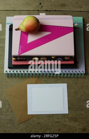 a back to school concept still life with school supplies and a ripe pear on a wooden table Stock Photo