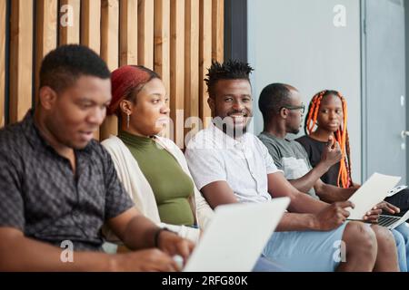 Bored business people sit on chairs waiting for an interview Stock Photo