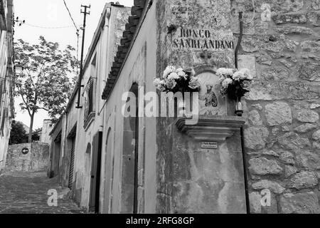 black and white street 'Ronco Sanrlandano' and votive aedicule in San Paolo District of Palazzolo Acreide, Sicily, Italy Stock Photo
