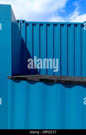 Colourful shipping containers used as cafes and bars on the Harbour Arm in Folkestone, Kent. Painted in a combination of deep blue and teal colours. Stock Photo