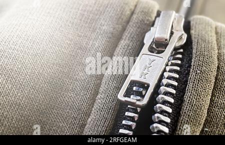 Rome, IT, Mar 15 2023: Close-up of YKK zipper on gray knit fabric with ribbed texture. YKK is the acronym for the Japanese company Yoshida Kogyo Kabus Stock Photo