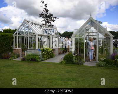 Visitors by greenhouses for sale on exhibitor's award-winning 'Feel Good' trade-stand display - RHS Tatton Park Flower Show 2023, Cheshire England UK. Stock Photo