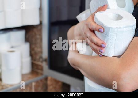 A woman holds many rolls of toilet paper. Stock Photo