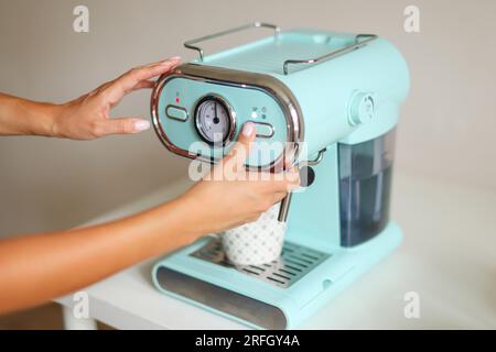Making coffee. Barista pushing button Start on a coffee machine Stock Photo