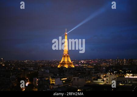 The Eiffel Tower lit up at night with the rotating beacon at the top over the city of Paris Stock Photo
