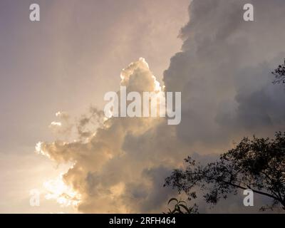 The sun hidden behind dense cumulus clouds, up in the sky above the eastern Andean mountains of central Colombia. Stock Photo