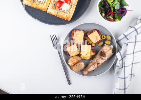 fried fish and a side dish of baked potato with cheese in plate for lunch on the table. Stock Photo