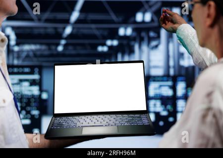 Close up shot of mock up laptop used by professional mechanic in data center server room delivering massive computing power, capable of processing and storing vast amounts of datasets Stock Photo
