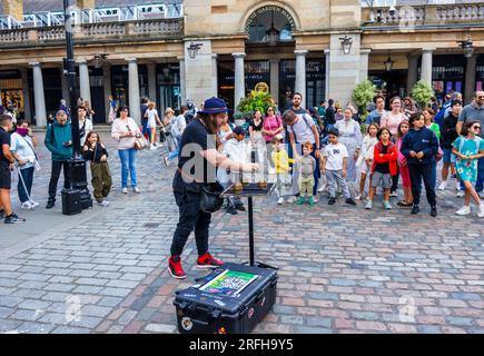 Australian street magician Jason Maher performs and entertains a crowd in Covent Garden in London's West End, WC2 Stock Photo