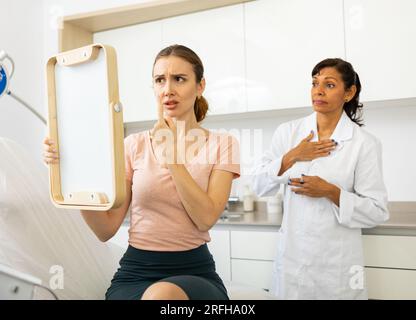 Dissatisfied woman checking result after cosmetology procedure Stock Photo