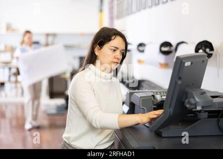 Technician operator calibrating plotter machine, typing on computer keyboard Stock Photo