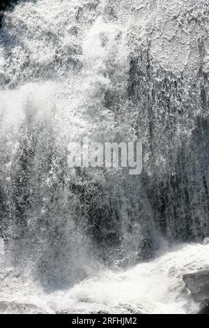 Close-up of a roaring waterfall crashing thunderishly down onto a rocky river bed. Stock Photo
