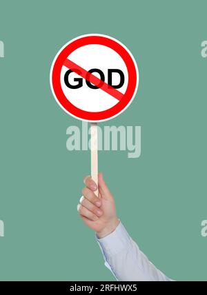 Atheism concept. Man holding prohibition sign with crossed out word God on pale green background Stock Photo