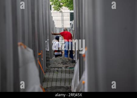 Berlin, Germany. 03rd Aug, 2023. Construction workers work on the memorial to the murdered Jews of Europe. Many of the more than 2700 concrete stelae of the Holocaust Memorial near the Brandenburg Gate show cracks. Credit: Hannes P. Albert/dpa/Alamy Live News Stock Photo