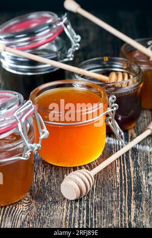 a spoon for honey together with high quality bee honey, an old table on which there is a healthy and sweet bee honey and a homemade wooden spoon that Stock Photo