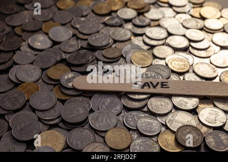 A close-up shot of Indian rupees coins spread on a table. The coins are arranged in a circular pattern, and the word 'save' is written in a stick on t Stock Photo