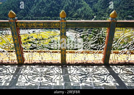 A decorative metal grille casts a shadow of the Buddhist eight-spoked wheel on the stone floor atop Khamsum Yulley Namgyal Chorten in rural Bhutan. Stock Photo
