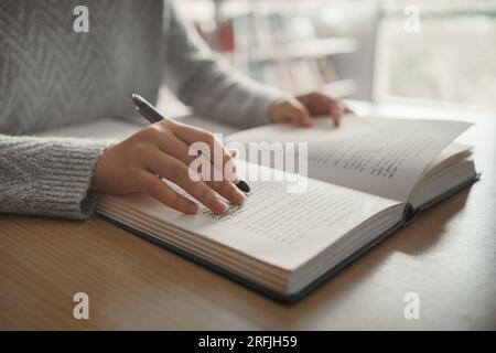 Student preparing for college test, exam, reading book, studying textbook, writing notes, making summary for class report. Learning workplace table, h Stock Photo