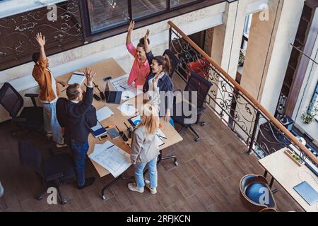 Smiling diverse business people vote with raising hands at corporate meeting. Team building Stock Photo