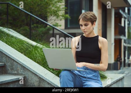 Female freelancer doing work tasks in urban environment Stock Photo