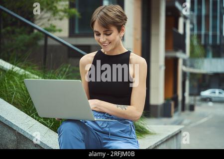 Female freelancer doing work tasks in urban environment Stock Photo