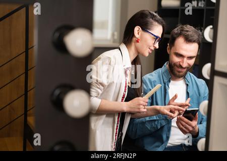 Man sits in barber chair in barbershop with mobile phone Stock Photo