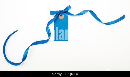 Blank blue price tag isolated on white background. Pastel color empty gift card and curly ribbon bow, copy space, Stock Photo