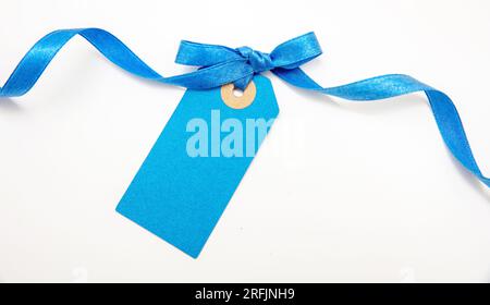 Blank blue price tag isolated on white background. Pastel color empty gift card and curly ribbon bow, copy space, Stock Photo