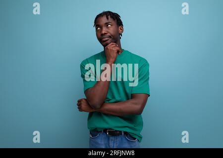 thoughtful smart american young man with dreadlocks in a casual green t-shirt on a background with copy space Stock Photo