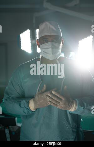 Portrait of biracial male surgeon wearing surgical gown in operating ...