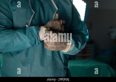 Biracial male surgeon wearing surgical gown using defibrillator in ...