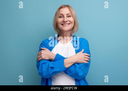 energetic 50s woman in an attractive look on a blue background with copy space Stock Photo